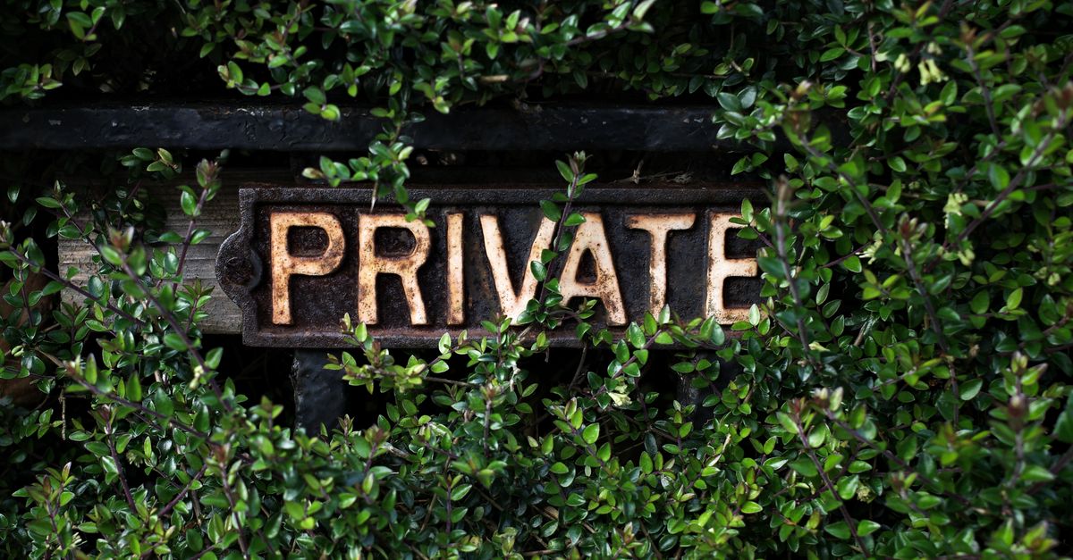 A rustic 'Private' sign nestled within lush green foliage, suggesting seclusion.
