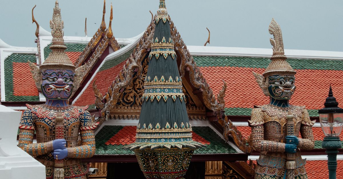 Colorful guardian statues at the Grand Palace, Bangkok, showcasing intricate Thai craftsmanship.