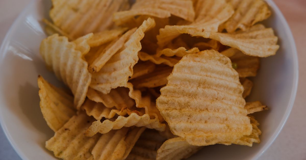 Delicious, golden ridged potato chips in a white bowl, perfect for snacking.
