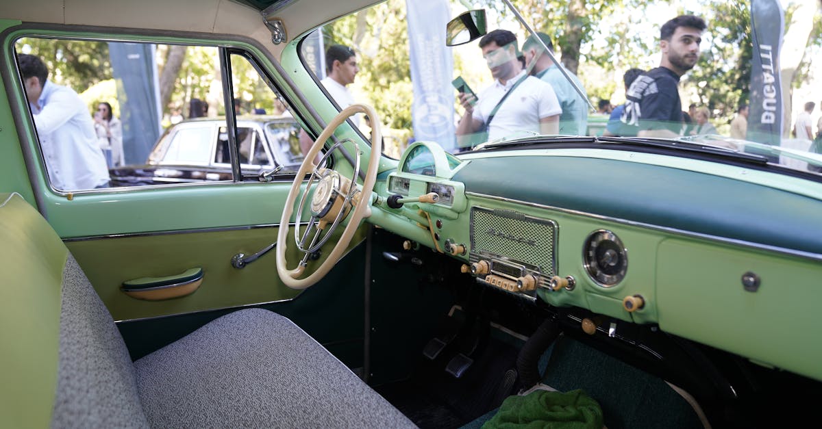 Interior of a vintage car with green accents showcased at an outdoor auto show.