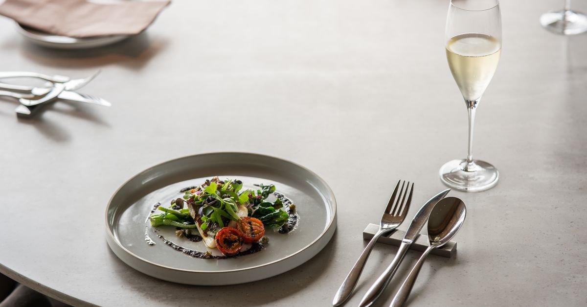 A sophisticated table setting with gourmet dish and champagne glass in a luxurious Tokyo restaurant.