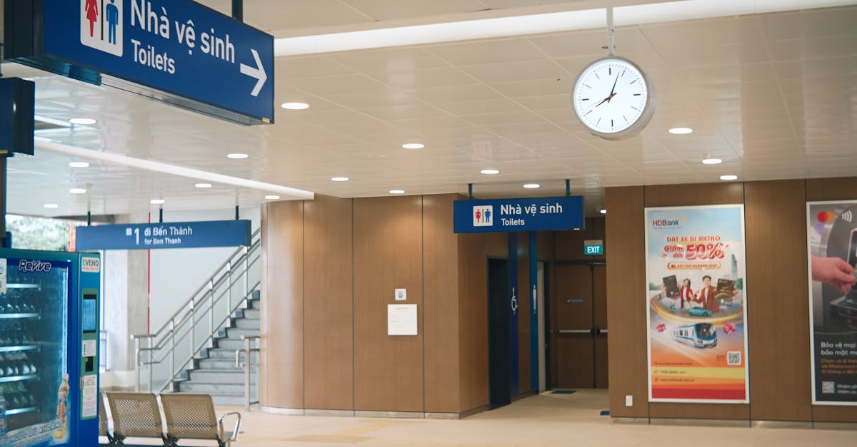Spacious indoor train station with clear signage for toilets and clock showing midday.