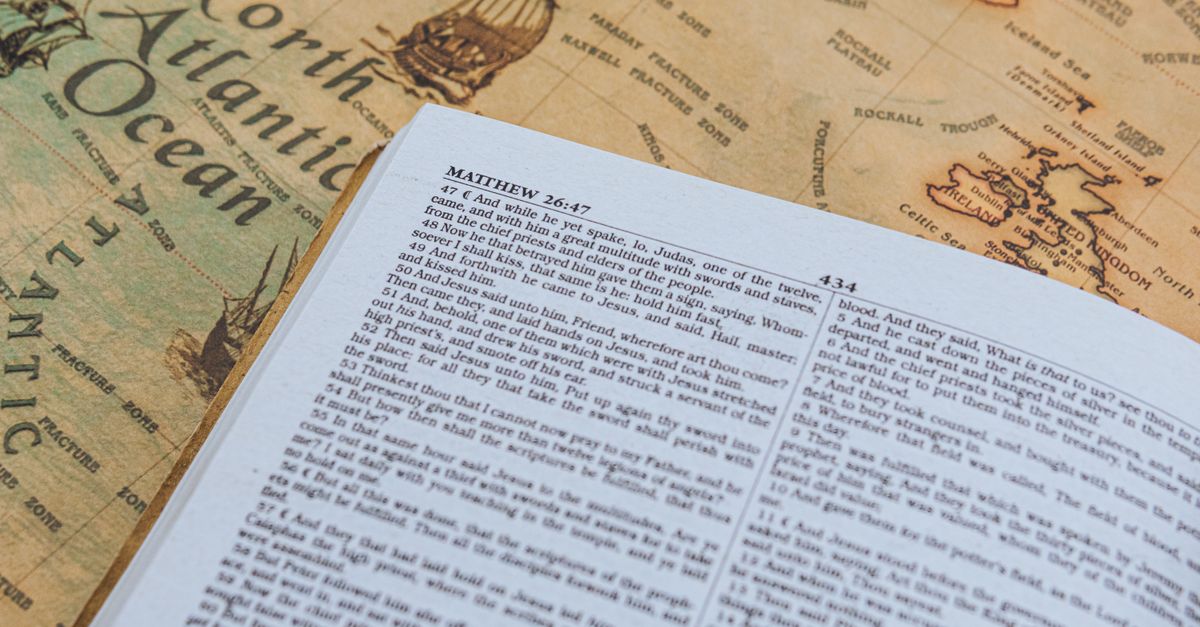 Open Bible with text from Matthew 26:47 on vintage map of North Atlantic Ocean.