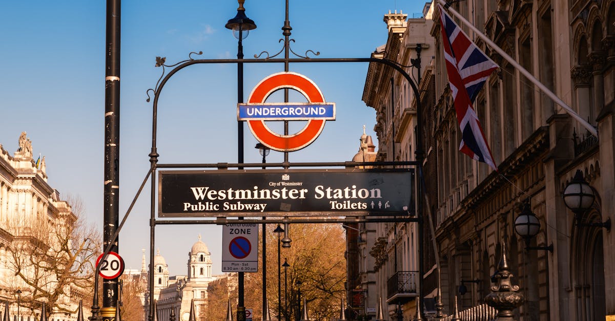 Iconic Westminster Station sign with classic London architecture and clear blue sky.