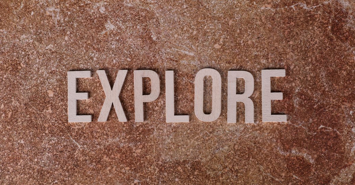 The word 'Explore' on a textured brown stone surface.
