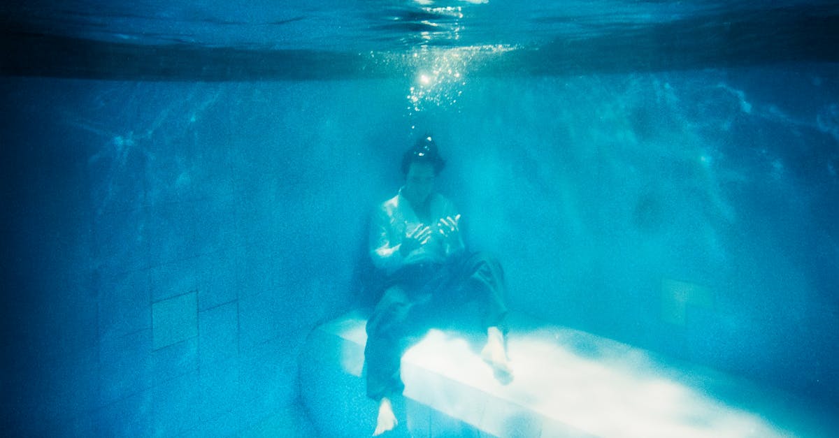 A person sits calmly underwater, surrounded by serene blue hues, creating a tranquil scene.