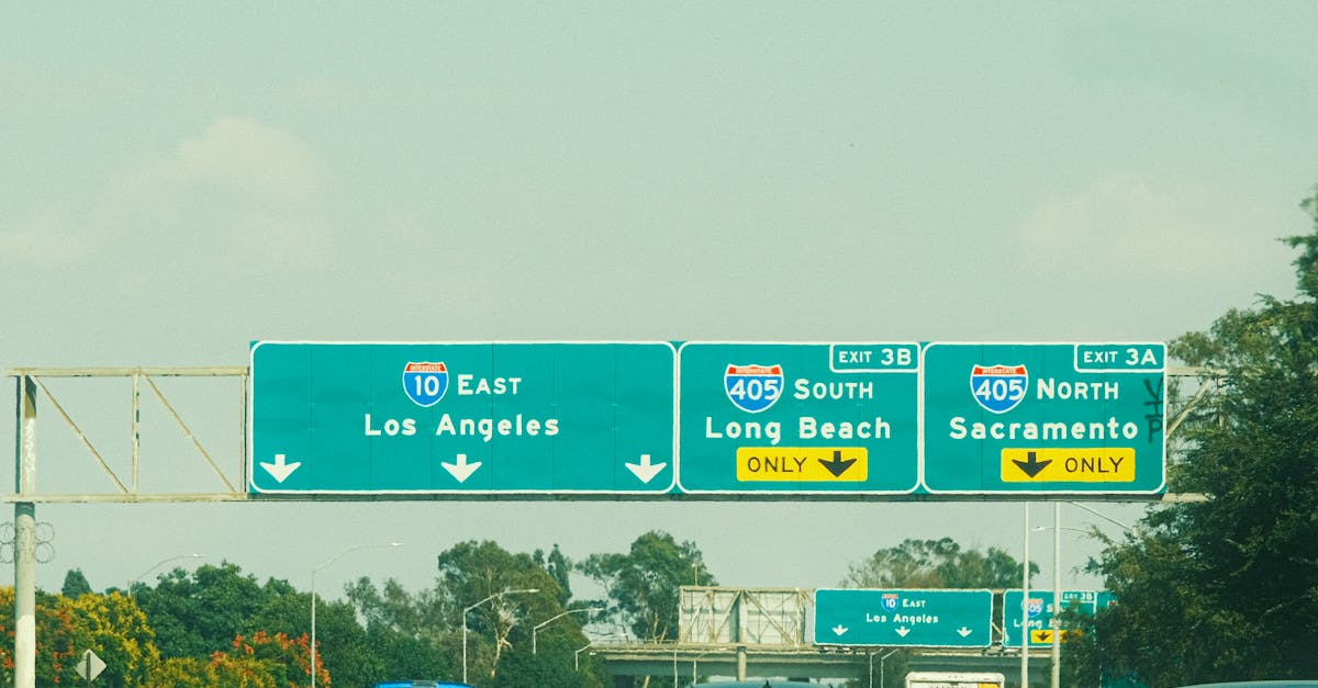 Highway signs with directions to Los Angeles, Long Beach, and Sacramento on a clear day.