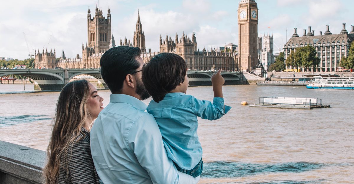A family admires the iconic Big Ben and Houses of Parliament from a riverside in London, capturing a serene moment.
