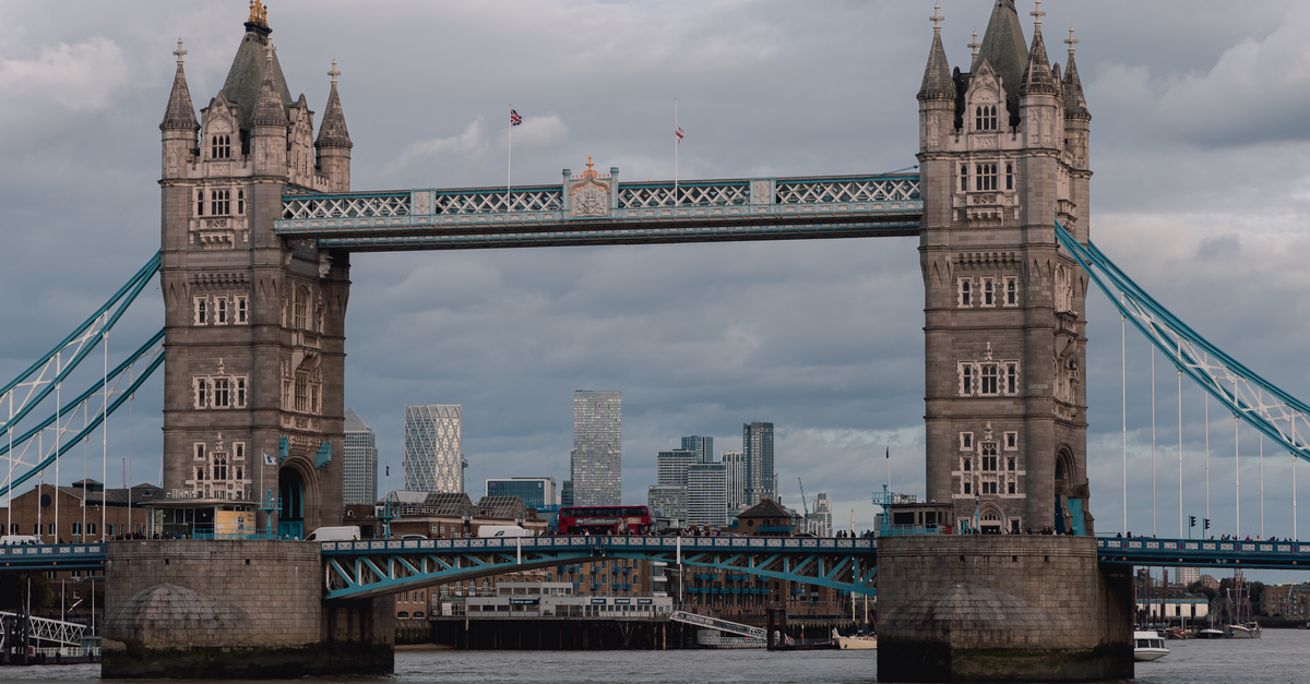 Iconic Tower Bridge view with Thames River in London, capturing classic architecture against a moody skyline.