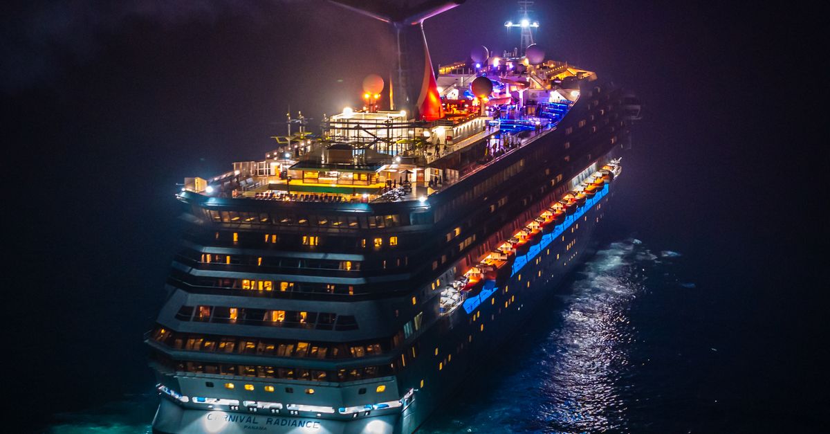 Stunning aerial view of a colorful, illuminated cruise ship navigating the ocean at night.