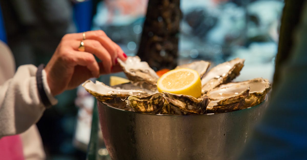 Hand reaches for fresh oysters with lemon at an Irish seafood restaurant.