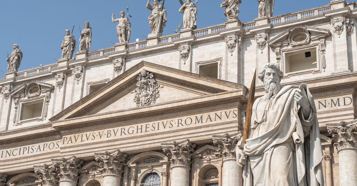 Statues of apostles adorn the facade of St. Peter's Basilica in Vatican City under a clear blue sky.