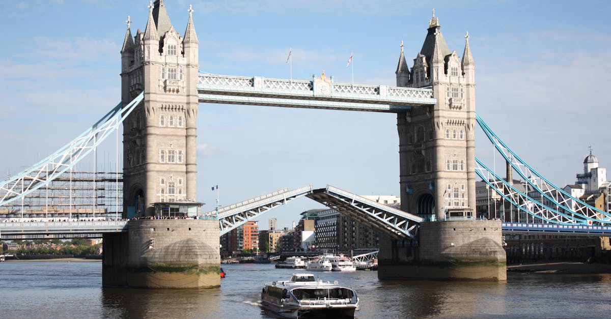 Tower Bridge raised for a boat on the River Thames in London, England, against a clear blue sky.