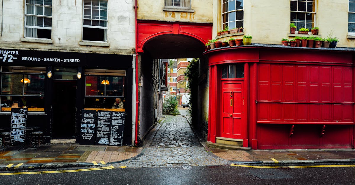 Quaint cobblestone street between two buildings with a cafe and vibrant red facade.