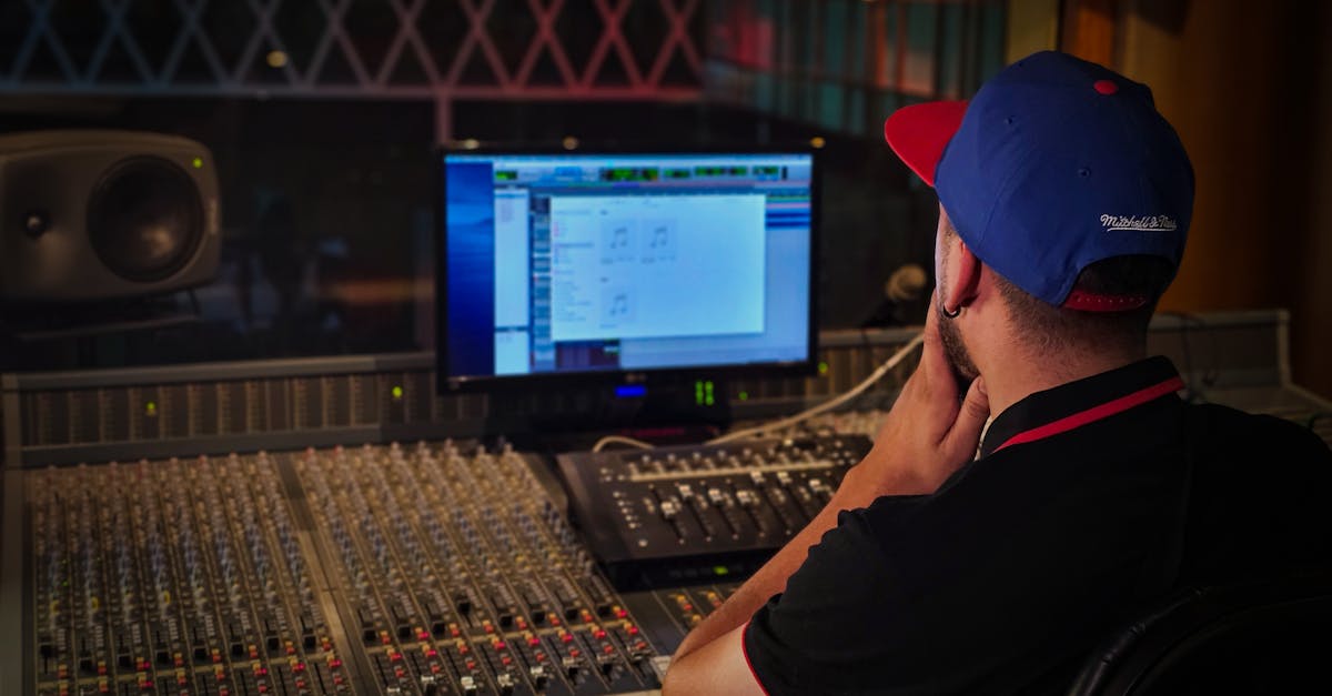 Audio engineer working at mixing console in cozy recording studio with ambient lighting.