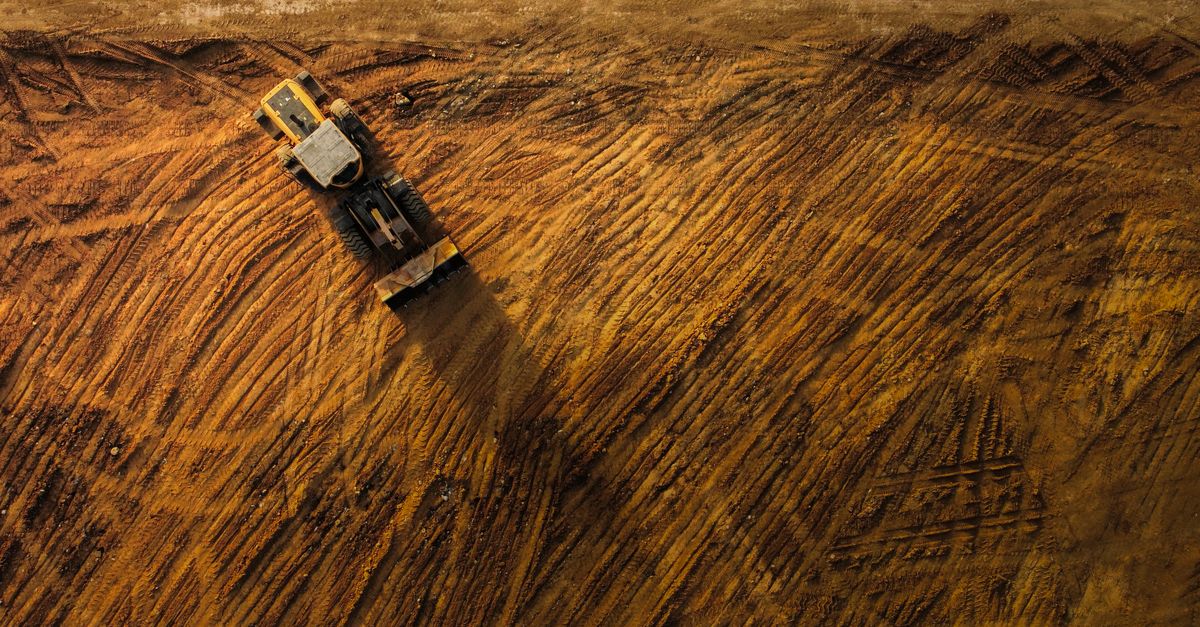 Top-down view of a bulldozer moving earth on a large construction site.