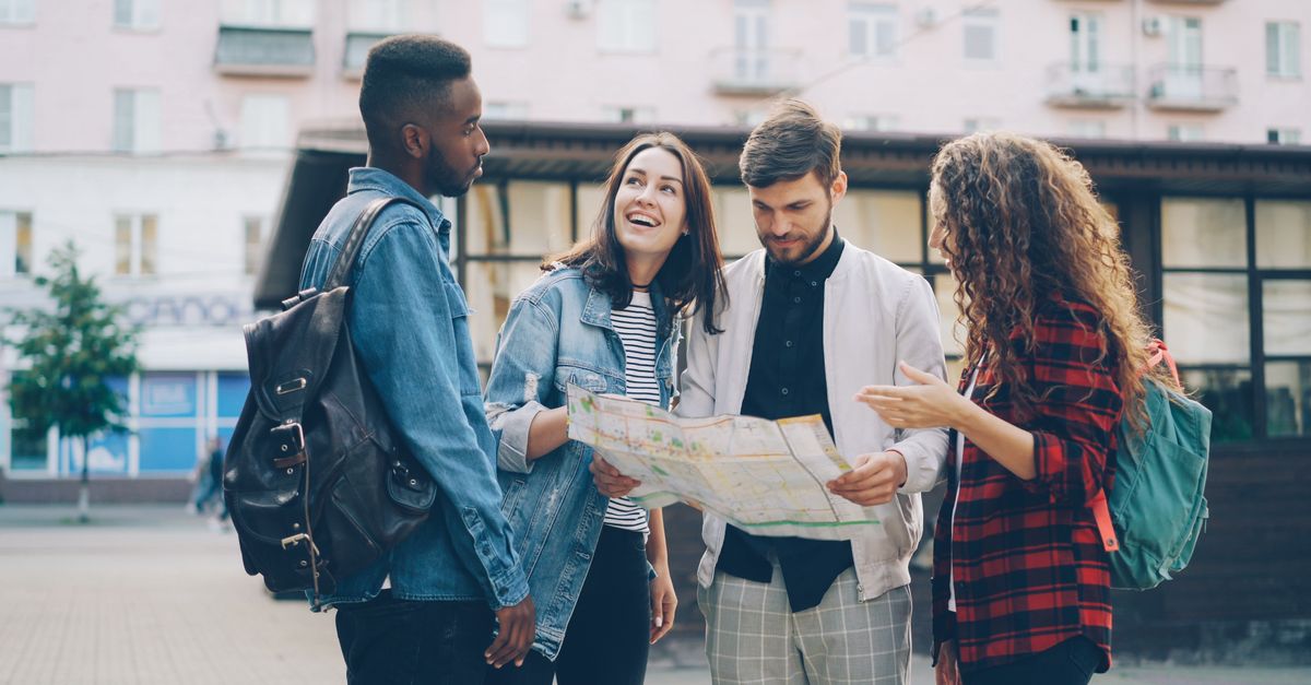 Four young friends reading a map outdoors, planning their city adventure.