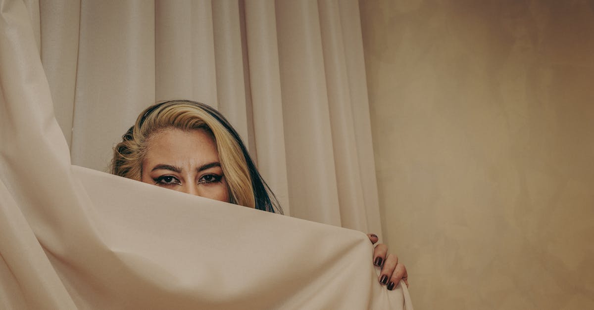 A captivating portrait with a focus on eyes behind a neutral curtain, evoking mystery.