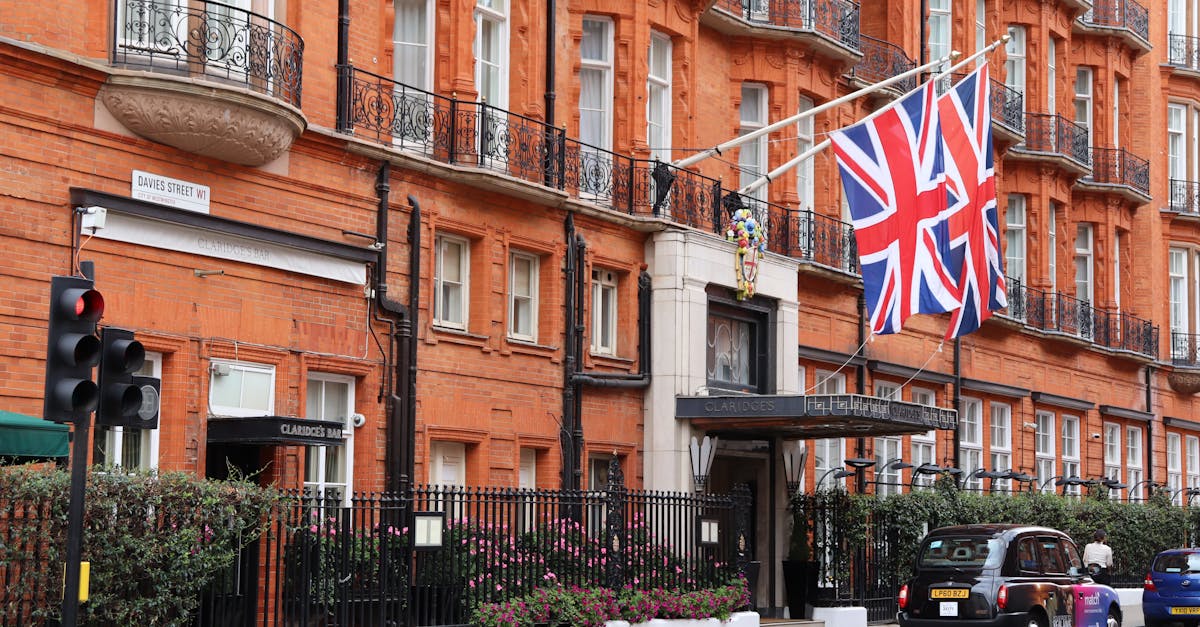 Exterior of classic London hotel on a busy street with Union Jack flags displayed.