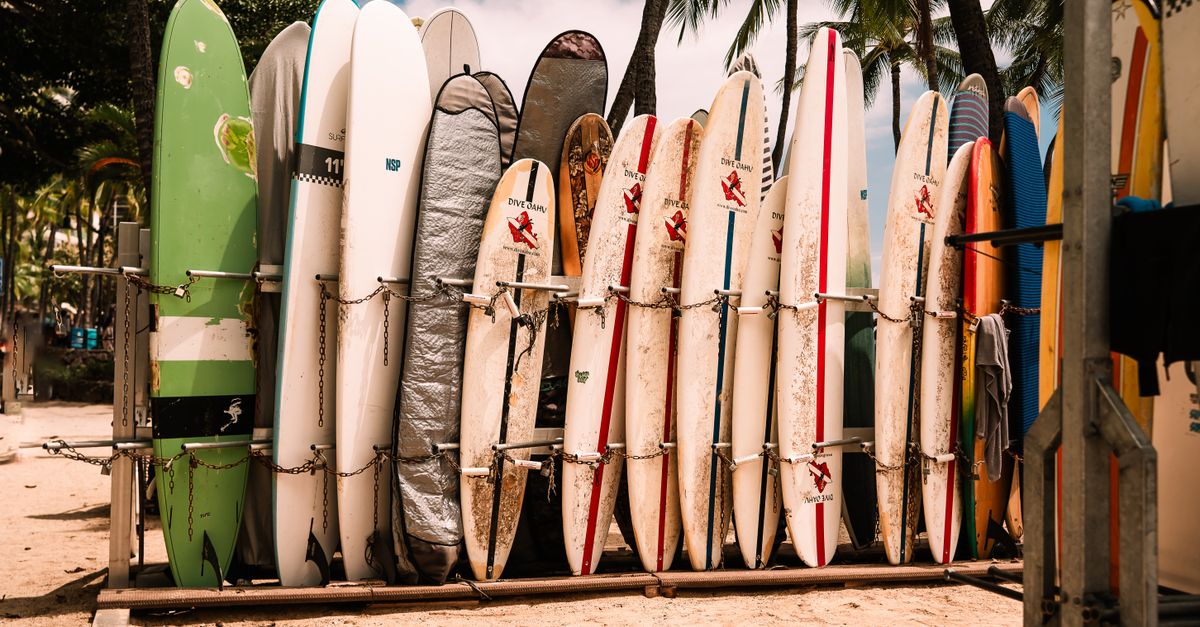 Colorful surfboards on display at Waikiki Beach, Honolulu under palm trees and blue sky.