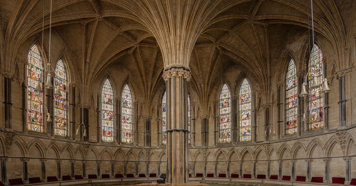 Stunning gothic interior of the Chapter House in Lincoln Cathedral, England, showcasing intricate architecture and stained glass windows.