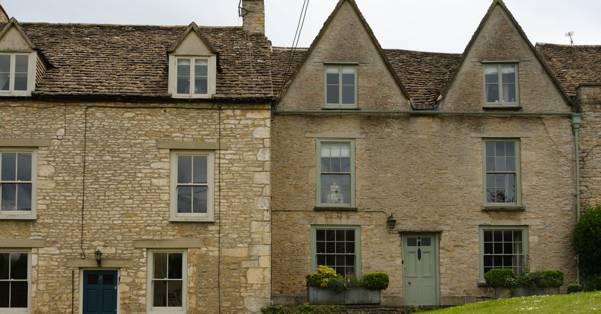Quaint stone houses with steep roofs in the serene English countryside landscape.