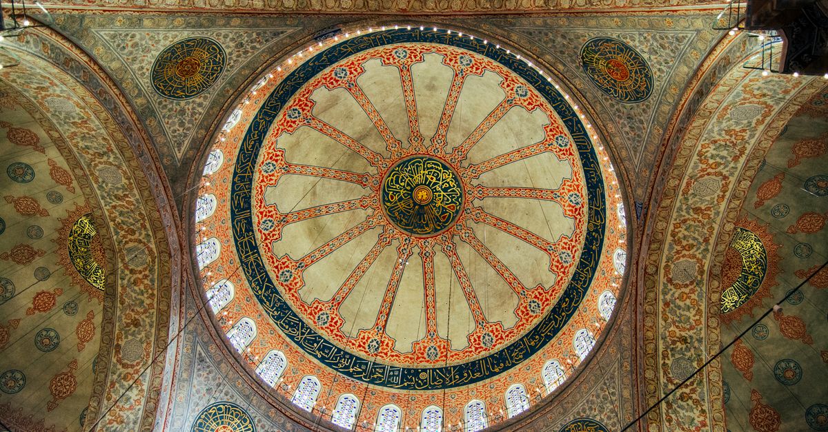 Beautifully detailed dome interior showcasing intricate Islamic art and calligraphy.