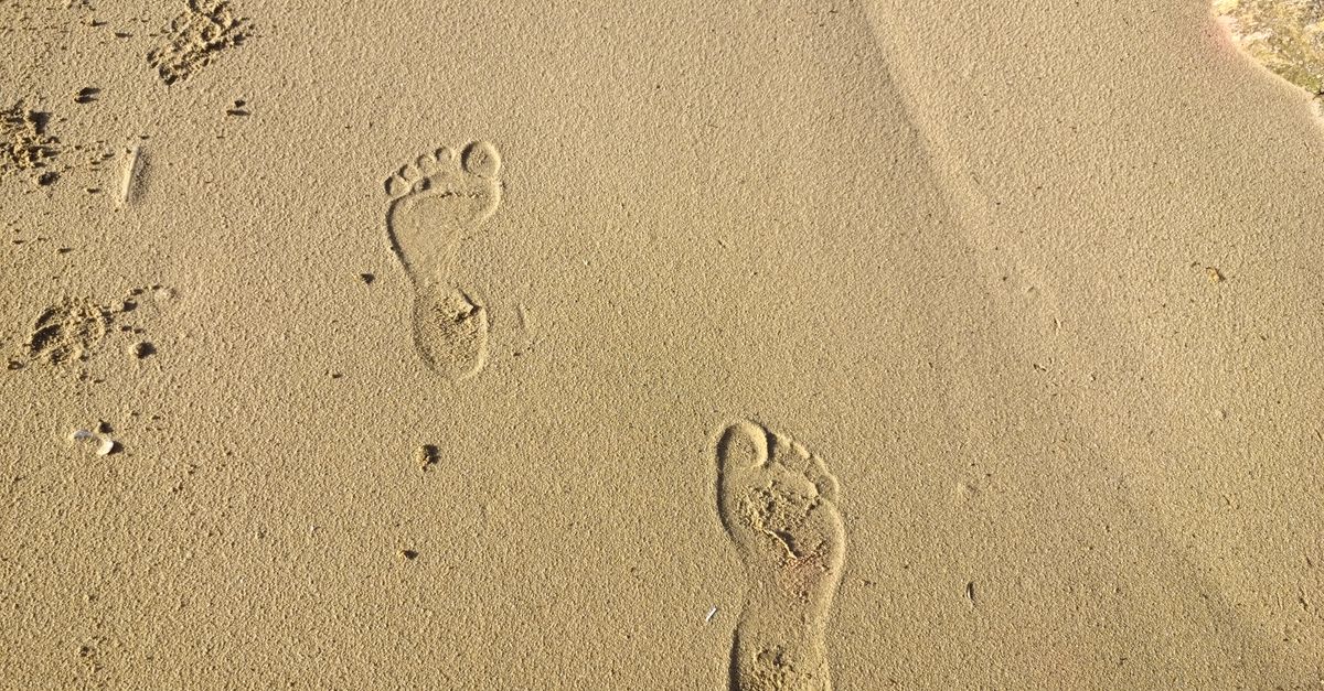 Footprints in the sand at El Puerto de Santa María beach on a sunny day.