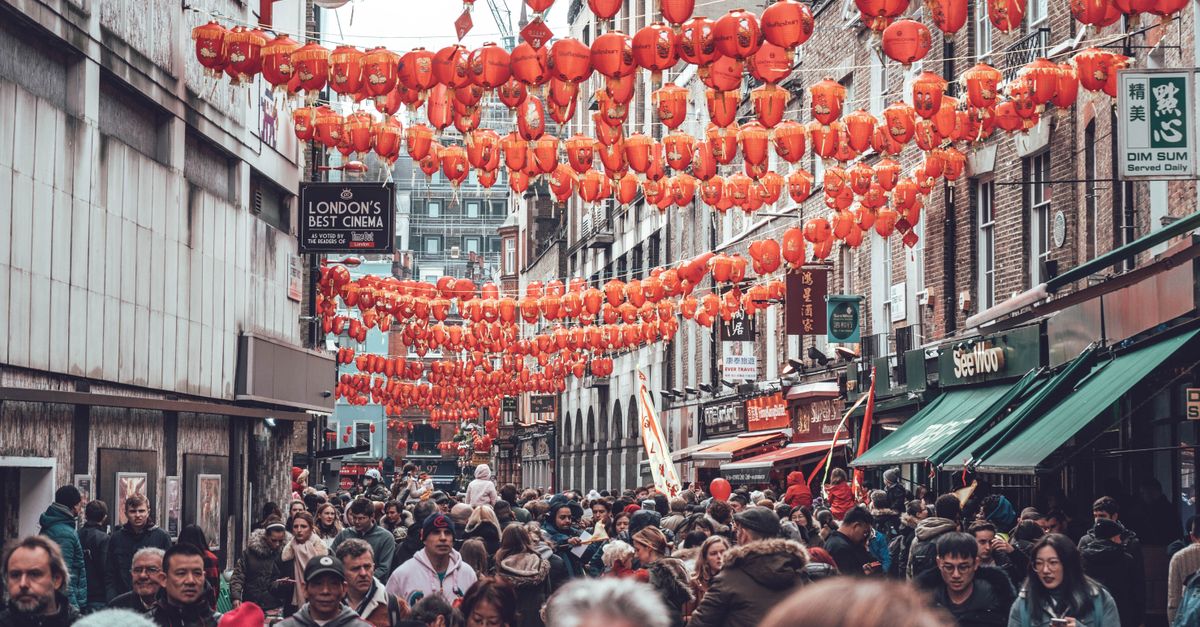 Crowded street in London's Chinatown adorned with traditional red lanterns, capturing vibrant cultural atmosphere.