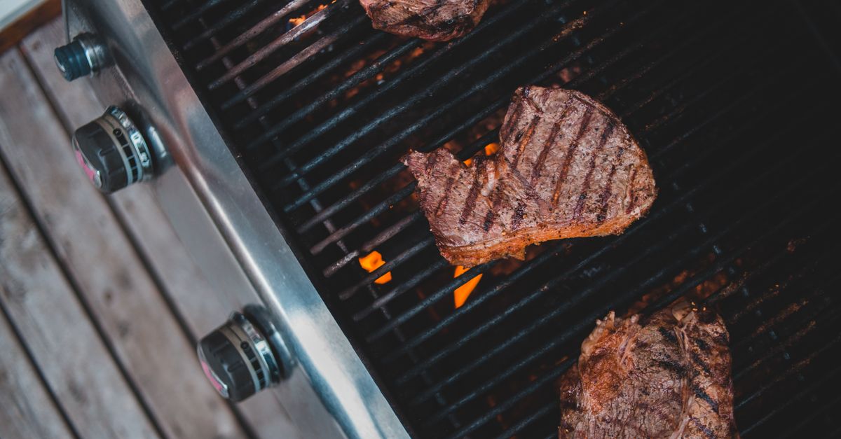 Top view of delicious steaks roasting on hot grill during picnic in yard