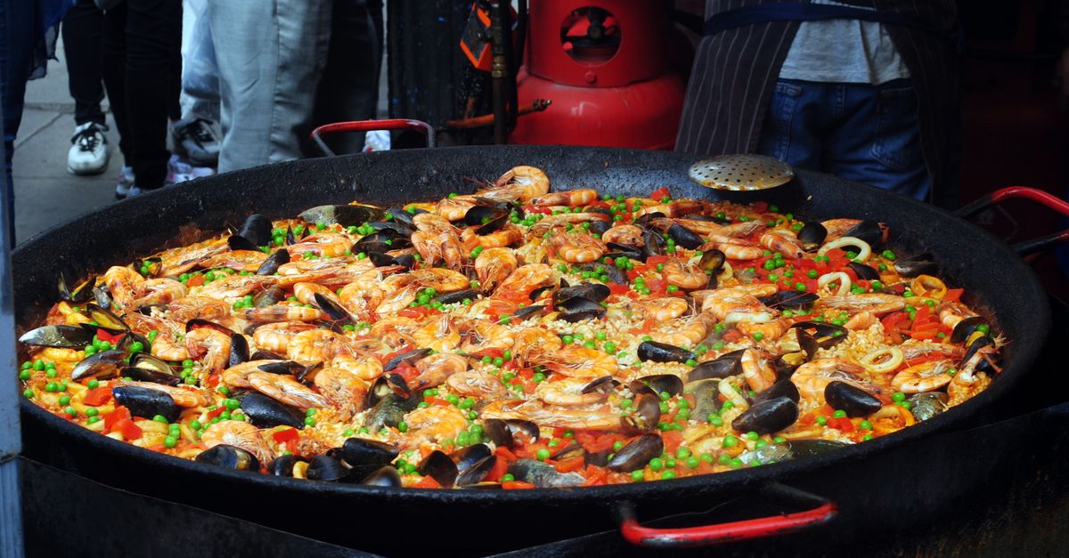 From above of traditional tasty Spanish dish with rice and bright chopped vegetables decorated with shellfish