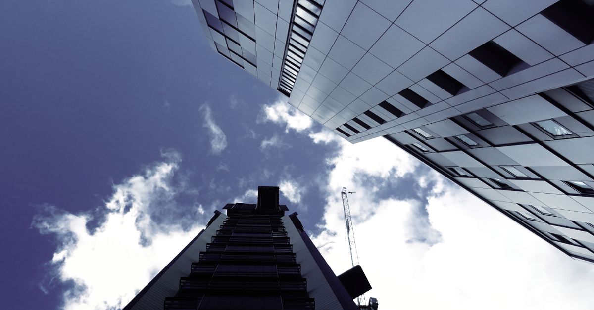 Low angle view of modern skyscrapers with a construction crane and clouds in the sky.