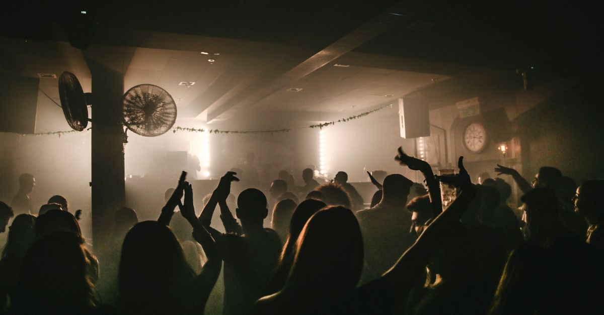 A lively dance floor with people enjoying music in a dimly lit nightclub environment.
