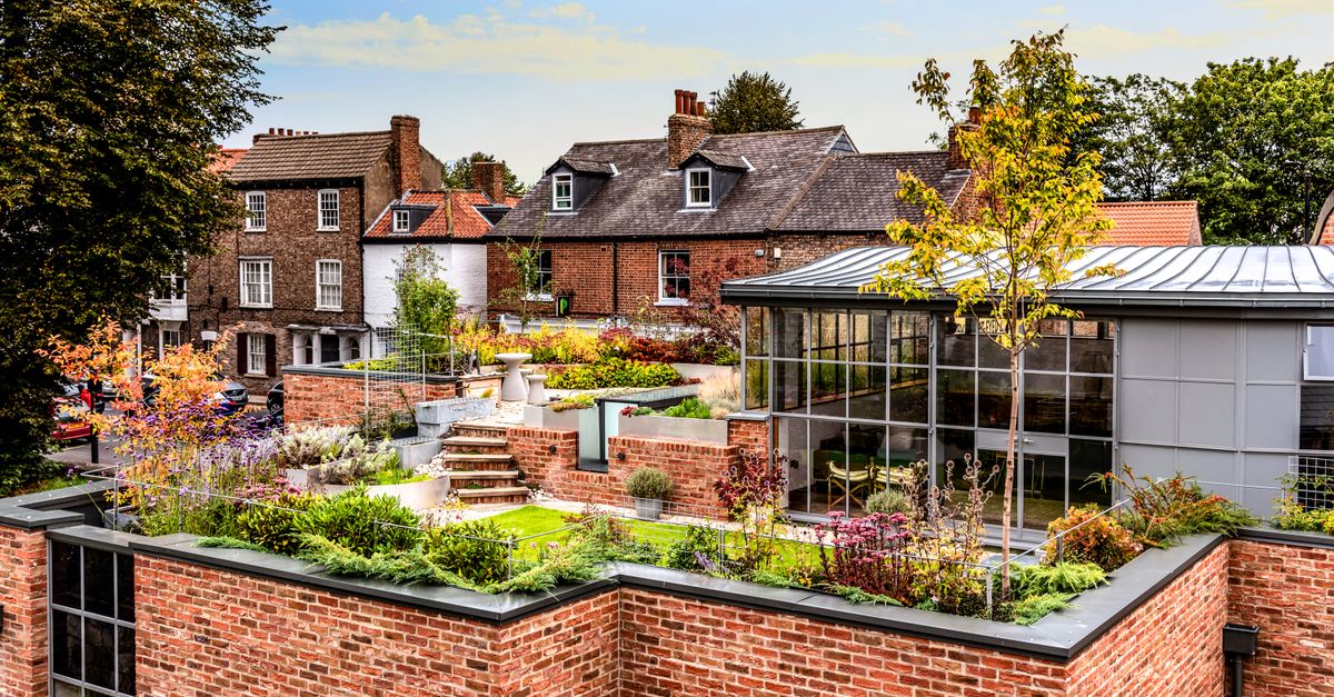 A beautiful rooftop garden on red-brick buildings under a clear sky.