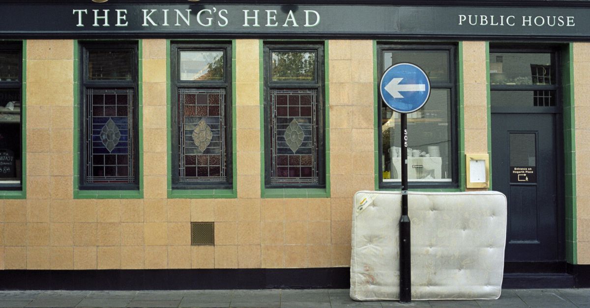 The King's Head public house facade with stained glass and a mattress on the sidewalk.