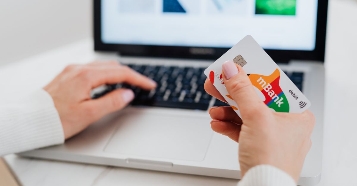 Close-up of hands using a laptop and holding a credit card for an online transaction.