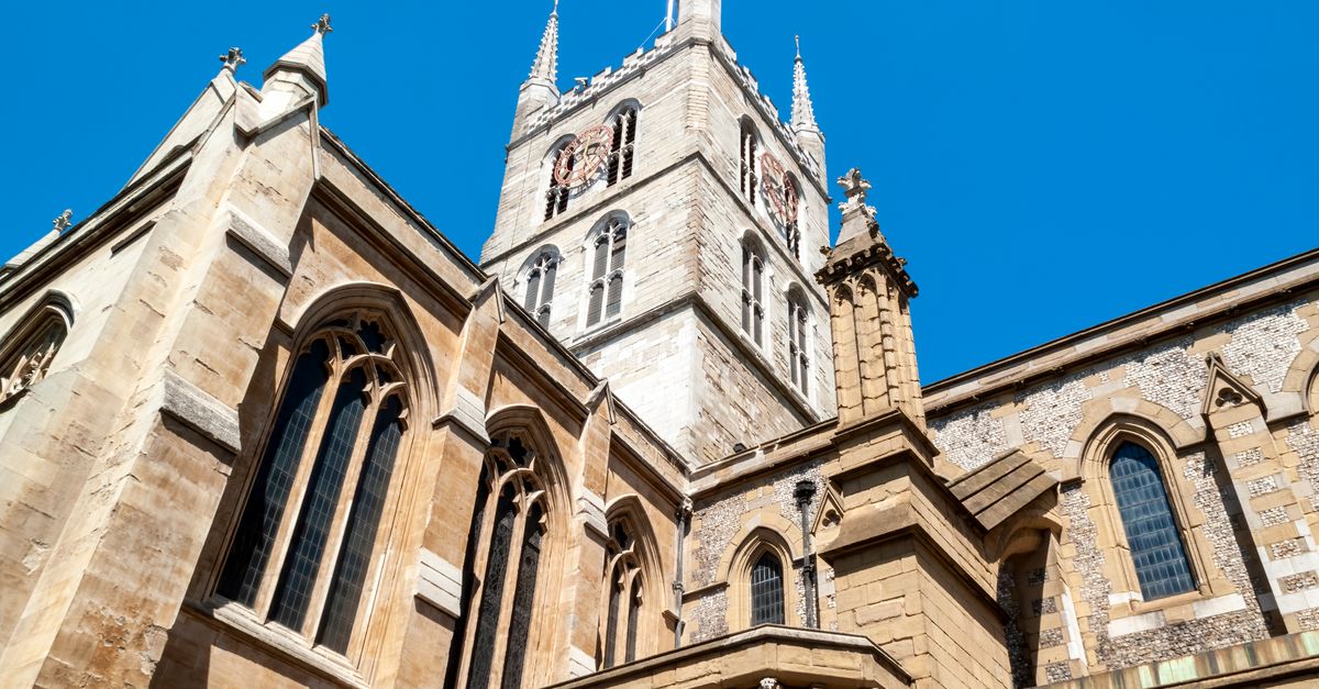 Low angle view of Southwark Cathedral's Gothic architecture against a clear blue sky in London.
