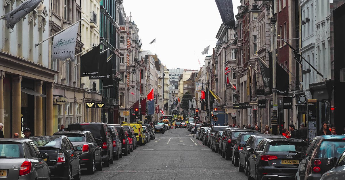A busy street lined with parked cars and bustling shops in central London, UK.