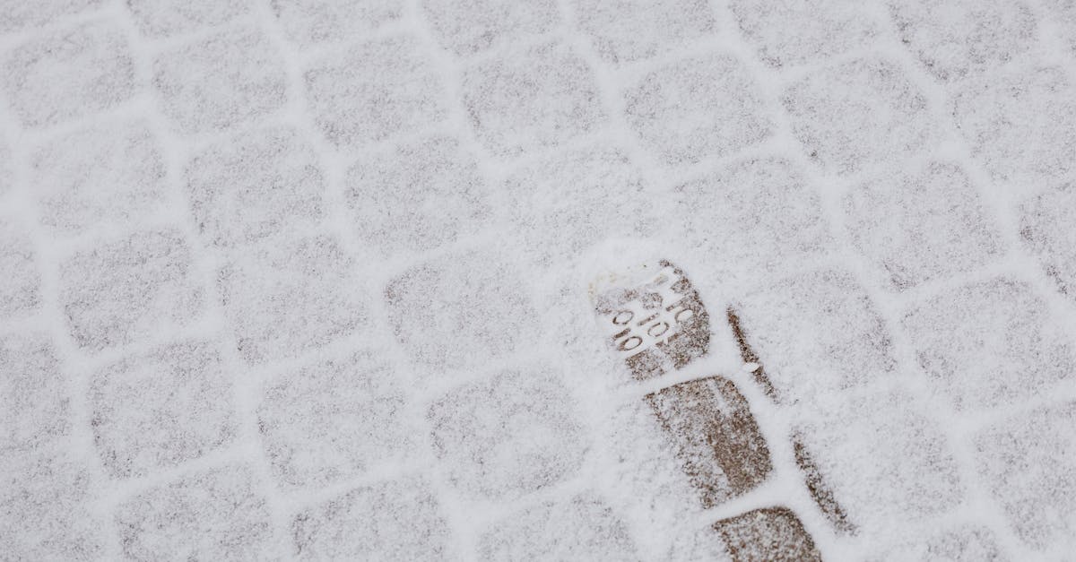 Close-up of a footprint on a snow-covered cobblestone sidewalk in winter.