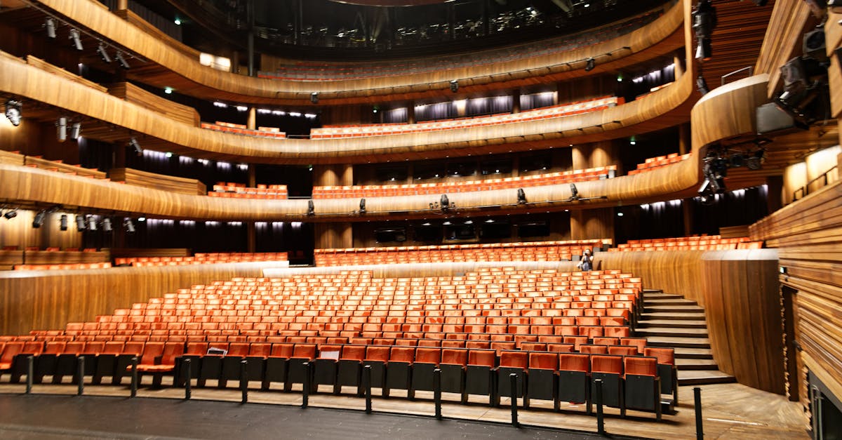 A spacious and modern indoor theatre featuring wooden interior and illuminated seating.