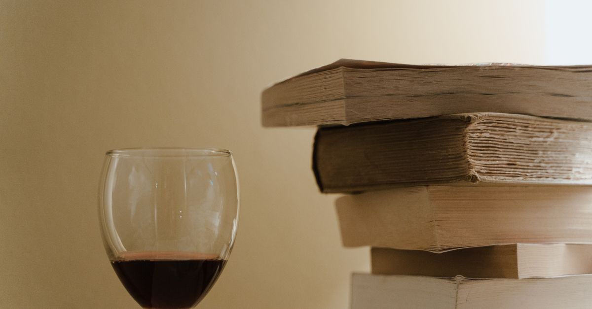 A serene still life photo featuring a stack of books and a glass of red wine, perfect for cozy reading vibes.