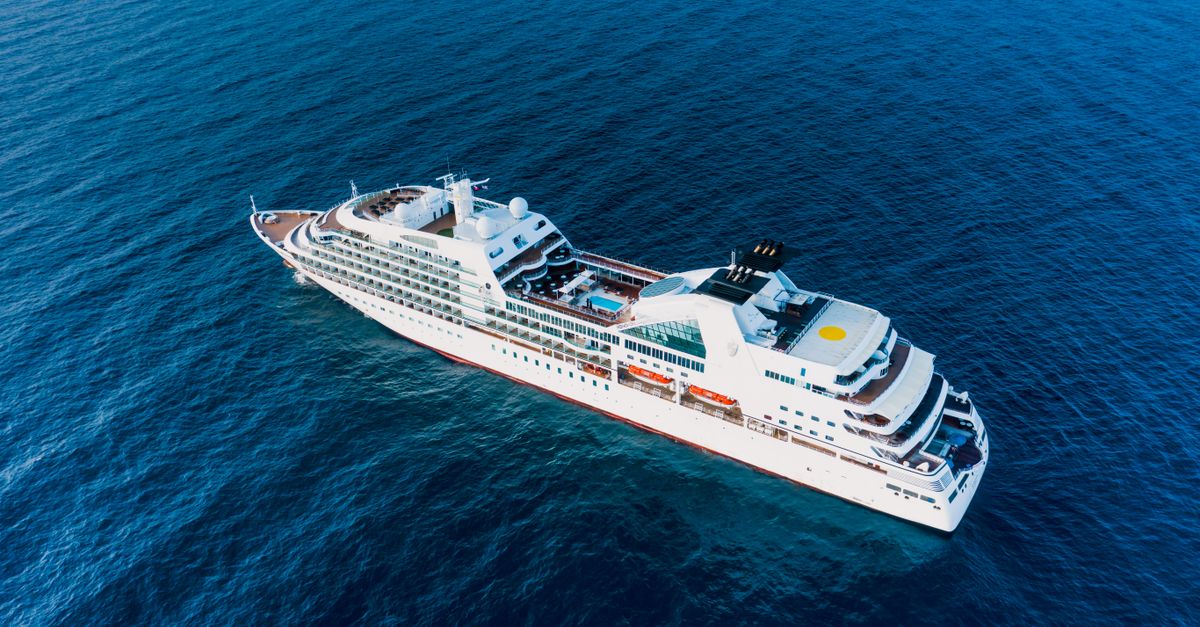 Drone view of luxury modern cruise ship floating on rippling blue water of ocean in sunny day