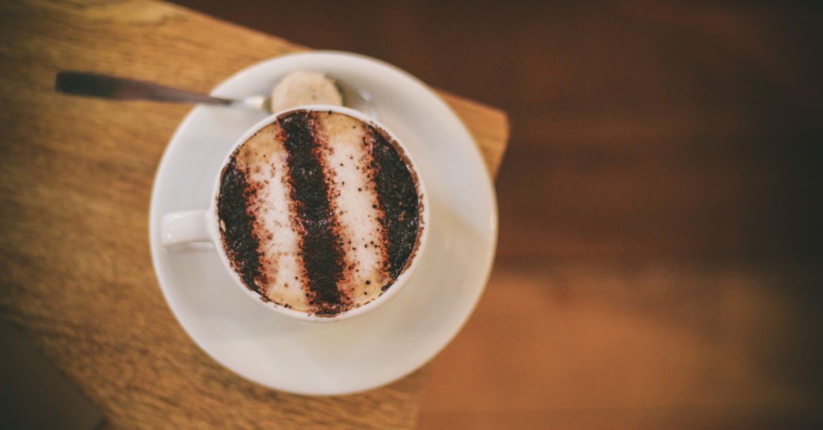 A high-angle view of a cappuccino with cocoa powder on a wooden table.