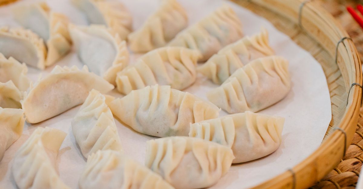 High angle closeup of wooden plate with set of delicious dumplings on white napkin