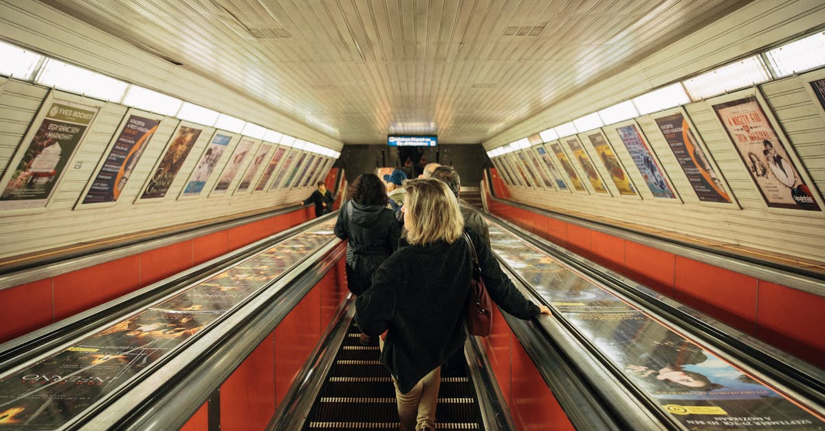 Commuters on an escalator in a Budapest metro station, Hungary, featuring vibrant posters.