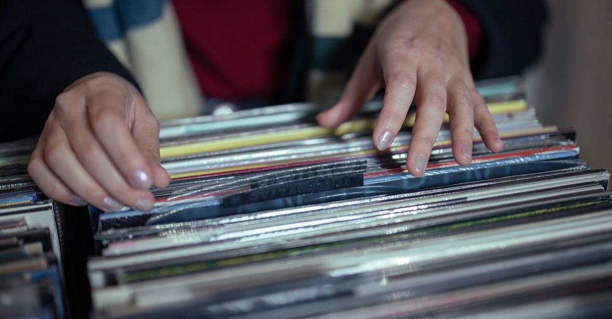 Hands browsing through a vintage vinyl record collection in a music store.