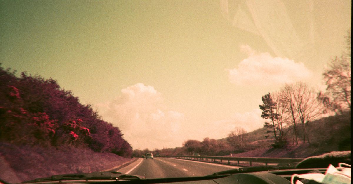 View from car driving on a scenic rural highway under a clear sky.