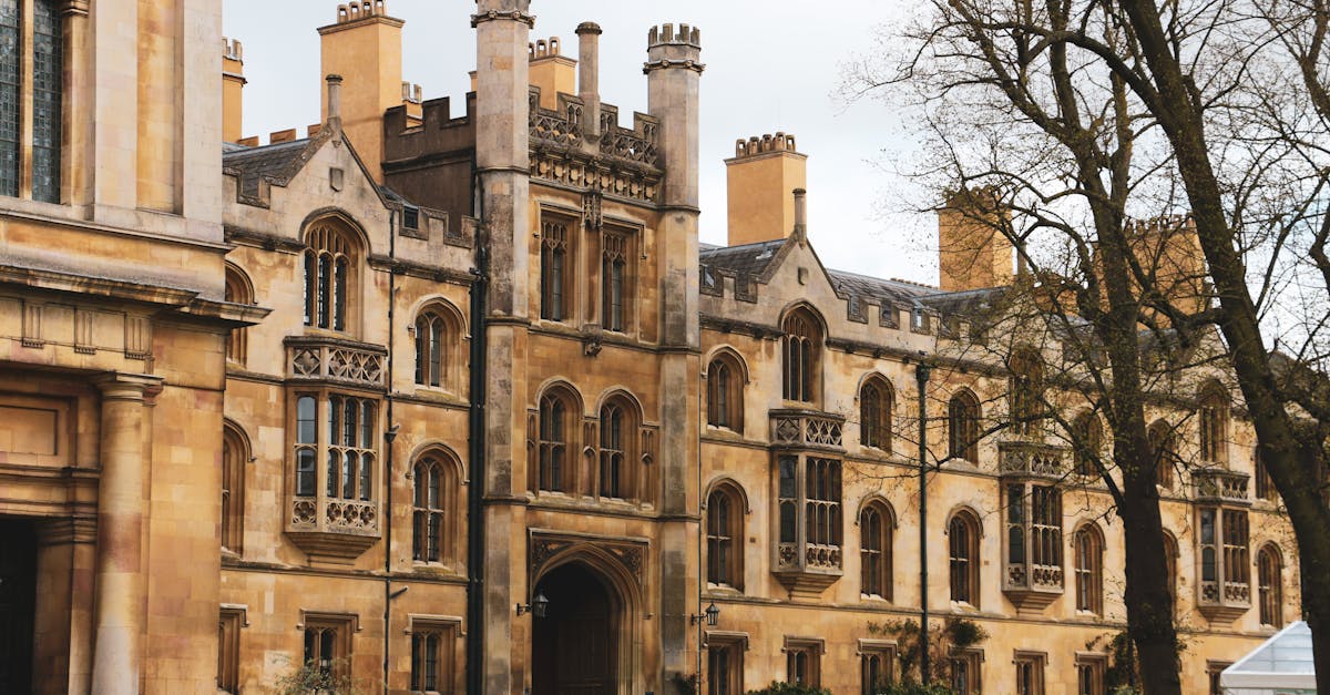 Elegant historic building facade with Gothic architecture and lush garden setting outdoors.