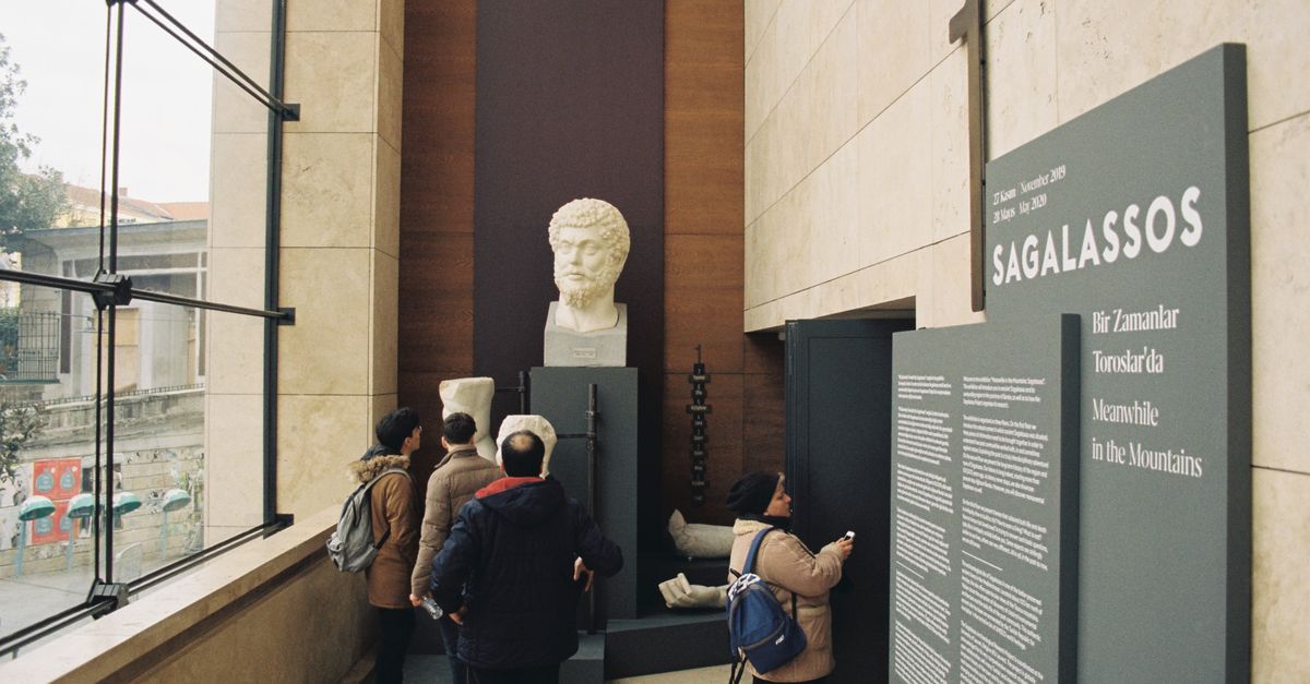 People viewing bust and artifacts at Sagalassos exhibit in a museum.