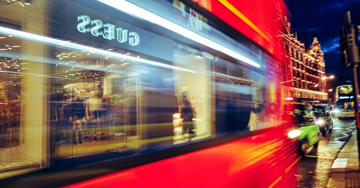 Dynamic urban night scene with a blurred red bus and illuminated streetlights showcasing city life.
